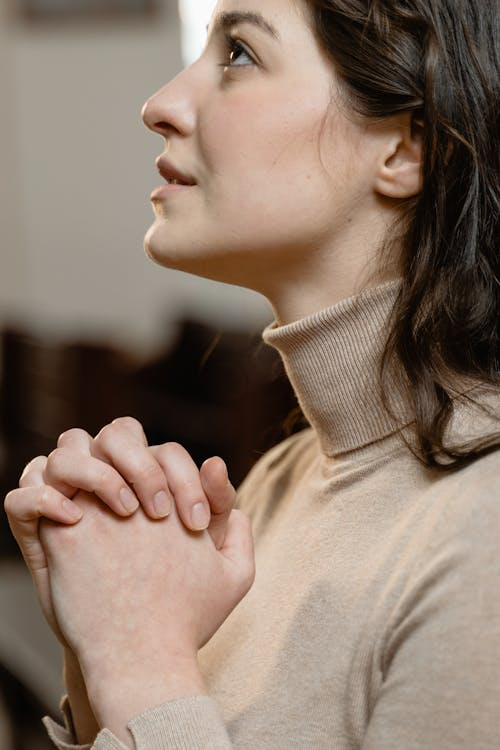 An image of a woman praying with joined hands.