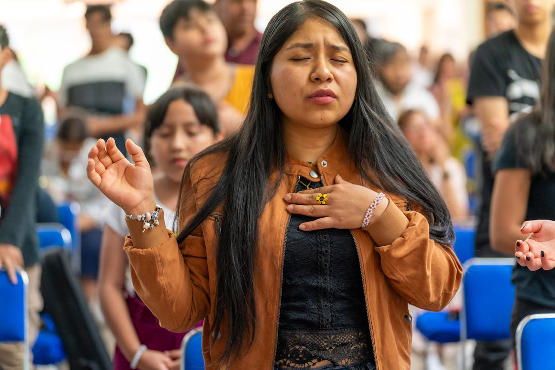 An image of a woman praying in a church.