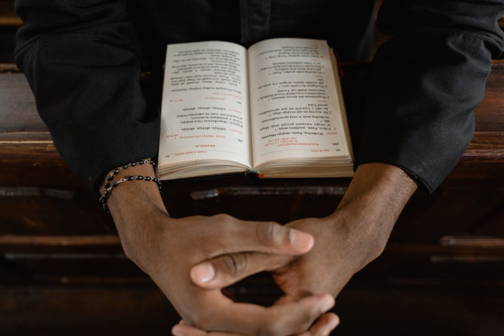 An image of a person with their hands together and the Bible in front of them