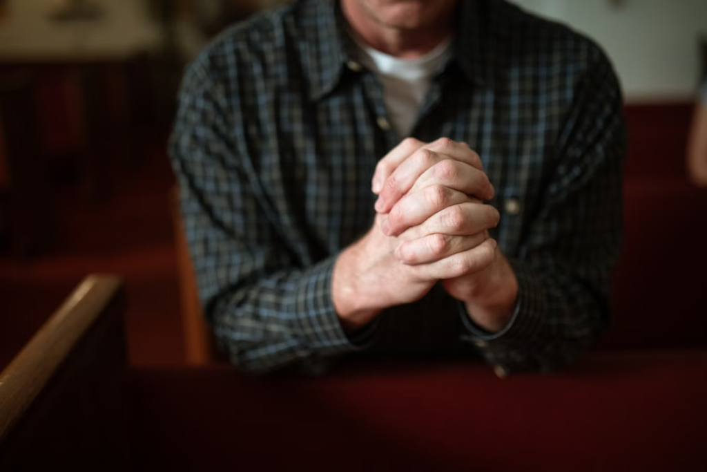 An image of a man praying in a church  